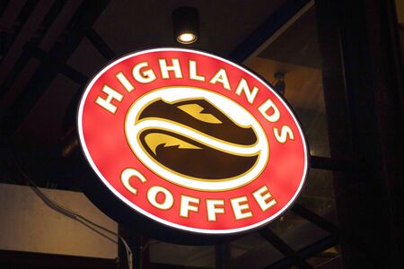 Danang, Vietnam - 26 Jul 2019: Highlands Coffee cafe logo lighting in darkness. Vietnamese coffee shop chain. Successful cafe franchise business. Coffee drinking culture in South Asia. Hipster placeのeditorial素材