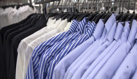 White and blue shirt on hang for sale in shop. Male wear on plastic hanger. Official wear for men in department store. Office apparel in shop. Sale in shopping mall. Nautical stripe pattern shirtsの写真素材