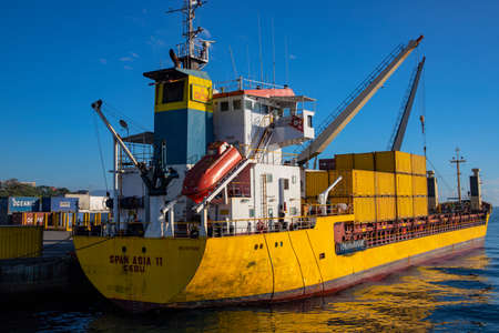 Dumaguete, the Philippines - 10 Mar 2020: yellow cargo ship in port, with containers loaded. Maritime shipping and delivery service. Goods and cargo transportation. Nautical vessel deck detailsのeditorial素材
