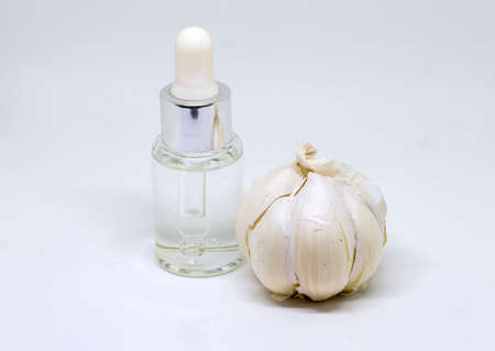 Medicine bottle and garlic on white background. Healthy diet concept photo. Medical or food supplement. Garlic essence or cosmetic ingredient. Old dry skin conceptual image. Cosmetology banner.の写真素材