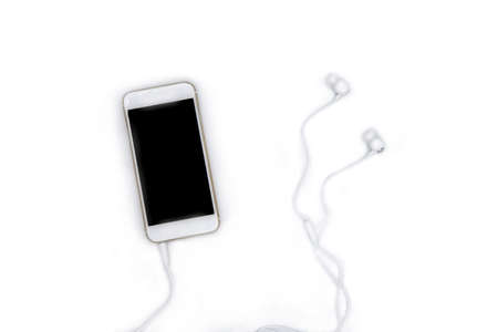 White phone with black screen and earphones top view on white background. Modern smartphone flat lay photo. UX app on phone screen mockup. Language or music listening concept. Stylish white gadgetの写真素材