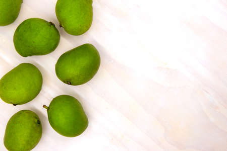 Apple mango on white wooden table, fresh fruit top view photo. Philippine green mango with sour sweet taste. Cooking healthy mango jam. Organic fruit on kitchen table. Summer diet. Tropical fruitの写真素材