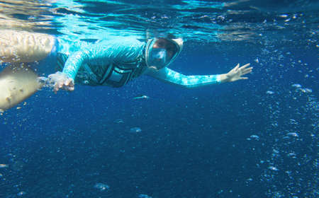 Young woman in snorkeling mask underwater photo. Snorkel in oxygen bubbles undersea. Snorkeling in tropical sea. Summer vacation outdoor activity. Tropical island adventure. Underwater banner templateの写真素材