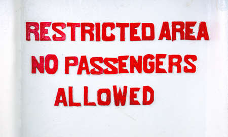 Red sign Restricted area No passenger allowed on white background. Prohibition for passengers of ship, vessel or boat. Rustic letters painted on white wall. Stencil typography prohibition signの写真素材