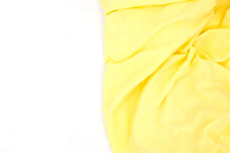 Yellow fabric on white background top view. Colored textile photo texture. Folded fabric with wrinkles for pattern mockup. Blank textile surface. Fashion or retail industry banner templateの写真素材