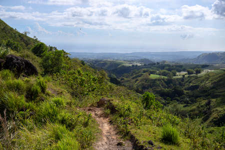Tropical island landscape with green hills and hiking path. Green summer nature scenic view. South Asia traveling. Hiking tour in the Philippines. Untouched environment of tropical islandの写真素材