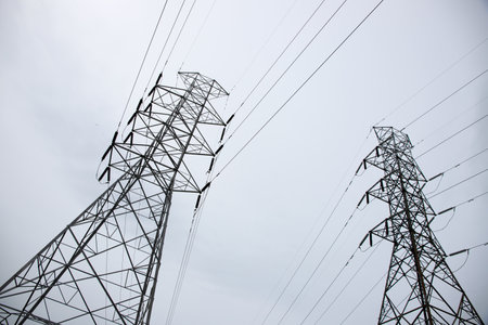 Electric towers and lines in fog. Telecommunication and internet provider equipment. Communication tower with wire line. Electrical pylon view from ground. Transmission tower skyscapeの写真素材