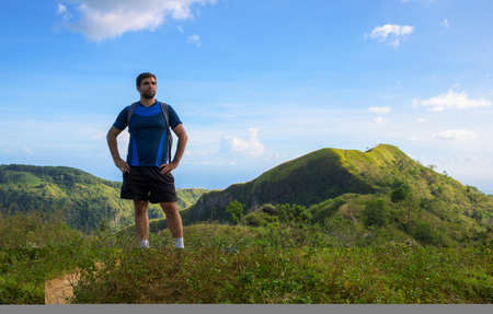 Man trekker on mountain landscape background. Summer countryside hiking trail view with male tourist. Man in treking or hiking outfit. Active lifestyle. Sport fit look in nature. Outdoor adventureの写真素材