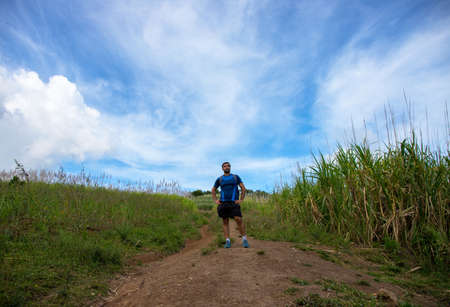 Trekker on trail on natural landscape background. Summer countryside hiking trail view with male tourist. Man in treking or hiking outfit. Active lifestyle. Sport fit look in natureの写真素材