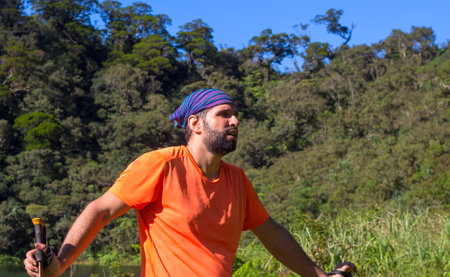Tired trekker on forest landscape background. Wild nature view with male tourist. Man in treking or hiking outfit. Active lifestyle. Eco-tourism banner template. Outdoor adventureの写真素材