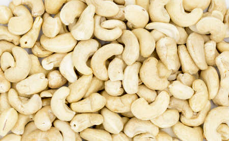 Raw cashew texture on white background. Natural organic nut kernel. Protein superfood or healthy snack. Cashew pile scattered on white table top view. White cashew package design. Healthy eatingの写真素材