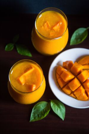 Mango juice with sliced Alphonso mangoes, Top view against dark background. Mango Smoothie. Traditional Indian Aamras. Two glasses. Dramatic Moody Concept Shot.の写真素材