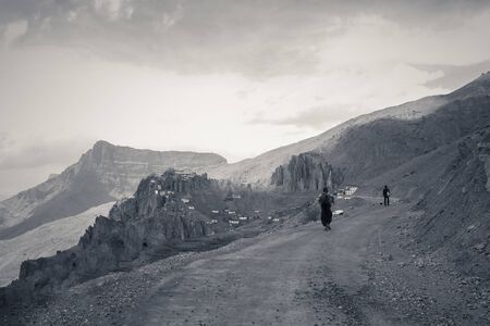 Two men walking towards Dhankar Gompa (also known as Dhankar Monastery) in Spiti valley, Himachal Pradesh, India. Serene backdrop with Martian-looking landscape and unusual rock formations. Explore the environment. Discover the beauty of the earth.の写真素材