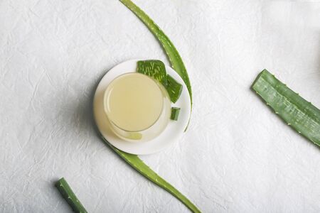 Fresh aloe vera juice on a white plate surrounded by aloe leaves, and sliced aloe veras, top view with space for text. Natural treatment for all types of skincare in Indian Ayurveda. Food Concept Shot.の写真素材