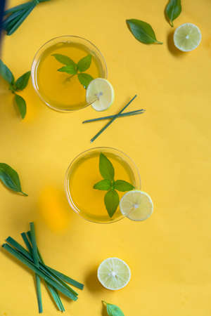 Herbal green tea with lemongrass in glass cup with fresh limes. Top view of two cups of Lemon Grass Drink on a Yellow Background.の写真素材