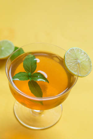 Herbal green tea with lemongrass in glass cup with fresh limes. Top view of two cups of Lemon Grass Drink on a Yellow Background.の写真素材