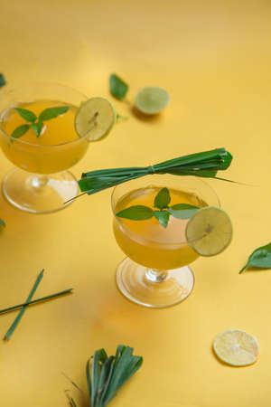 Herbal green tea with lemongrass in glass cup with fresh limes. Top view of two cups of Lemon Grass Drink on a Yellow Background.の写真素材