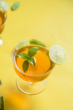 Herbal green tea with lemongrass in glass cup with fresh limes. Top view of two cups of Lemon Grass Drink on a Yellow Background.の写真素材
