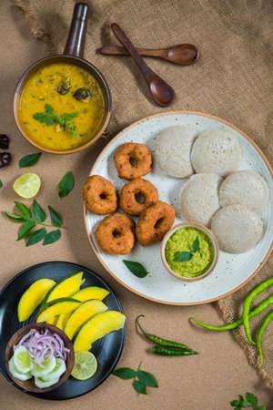 Top view of Idli, Wada, Sambar and Chutney. Traditional South Indian food, surrounded with lemon,...