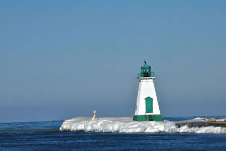Lighthouse on an ice covered pier on lake ontario,canadaの写真素材