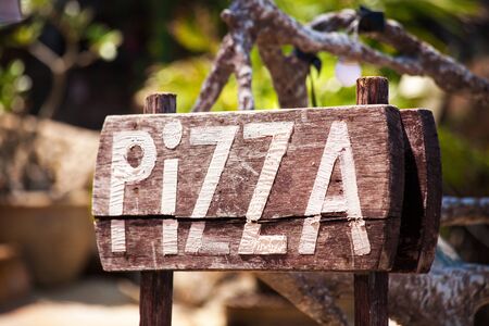 Big desk with letters Pizza on a wooden Board, landscape as backgroundの写真素材