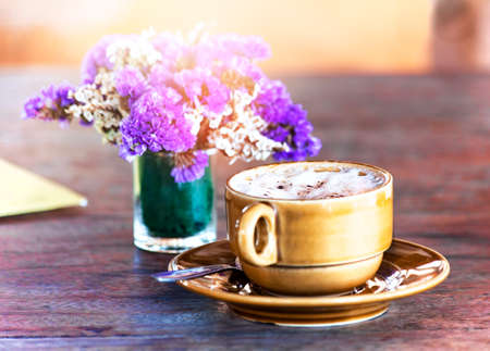 A purple bouquet on a wooden table, sun light, a cup of cappuccino, coloredの写真素材