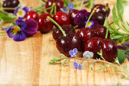 Cherries on a wooden table with water drops. With wildflowers.の写真素材
