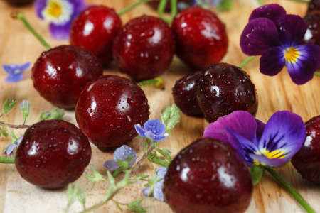 Cherries on a wooden table with water drops. With wildflowers.の写真素材