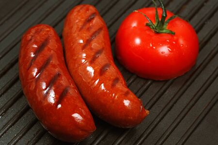 two sausages with tomato grilledの写真素材