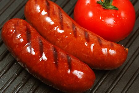two sausages with tomato grilledの写真素材