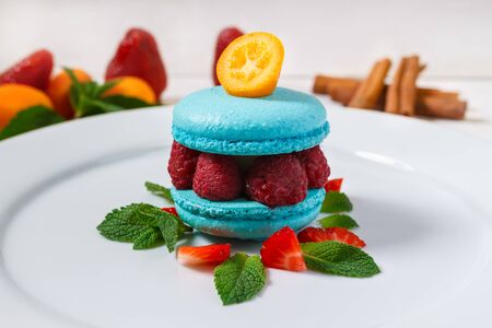 Blue macaroon with raspberries on a white plate decorated for restaurant menuの写真素材