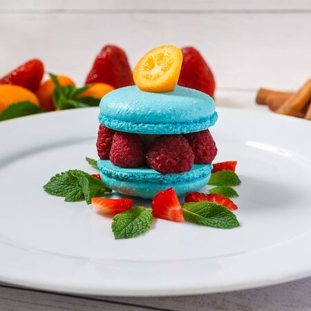 Blue macaroon with raspberries on a white plate decorated for restaurant menuの写真素材