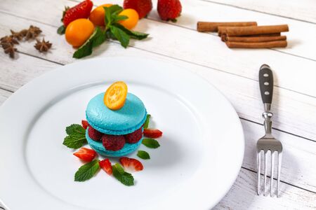 Blue macaroon with raspberries on a white plate decorated for restaurant menuの写真素材