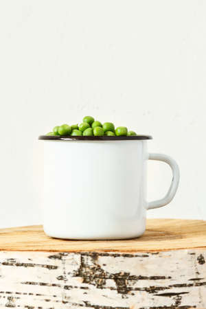 Fresh peas in iron bowl on a cut tree. verticalの写真素材