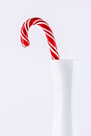 one red christmas candy in a white vase on white backgroundの写真素材