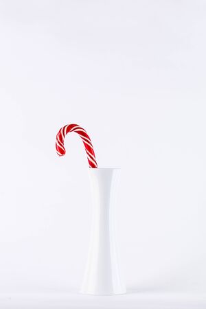 one red christmas candy in a white vase on white backgroundの写真素材