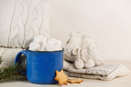 Marshmallows in blue mug on a white wooden table with ginger cookieの写真素材