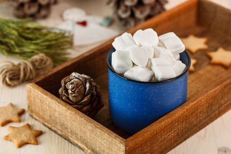 Marshmallows in blue mug in brown wooden box with ginger cookieの写真素材