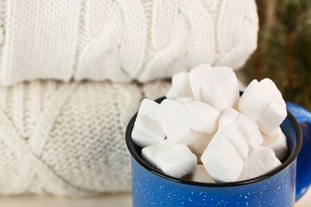 Marshmallows in blue mug on a white wooden table with ginger cookieの写真素材