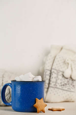 Marshmallows in blue mug on a white wooden table with ginger cookieの写真素材