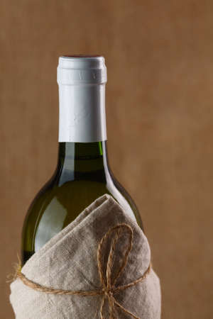 Bottle of white wine in textile on a texile brown backgroundの写真素材