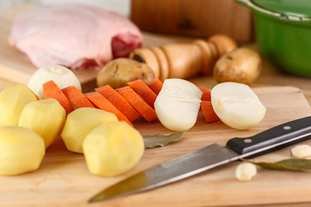 fresh peeled vegetables, potatoes, carrots, onions and chicken on the cutting Board with spices and knifeの写真素材