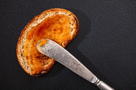 one toast with apple jam and knife on black background. Top viewの写真素材