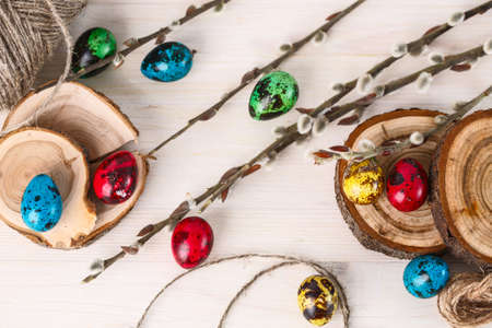 colored quail eggs for Easter and willow branches on white wooden tableの写真素材
