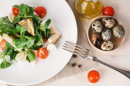 salad with quail egg, cherry tomato, crackers and corn salad on white background. Closeup. Top viewの写真素材