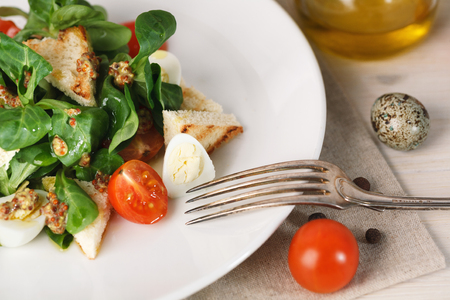 salad with quail egg, cherry tomato, crackers and corn salad on white background. Closeupの写真素材