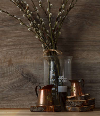 Still-life. Kitchen interior. copper measuring cups on wooden circles with willow branches on a wooden table. On brown wooden background. Springの写真素材
