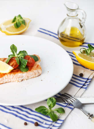 grilled salmon with cherry tomatoes, salad and lemon on white background. Top viewの写真素材