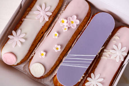 Traditional french eclairs on white table with pink flower