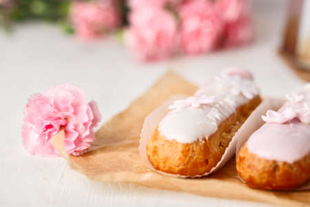 Traditional french eclairs on white table with pink flowerの写真素材